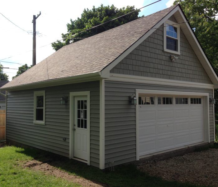 A garage with a gray siding and a white door