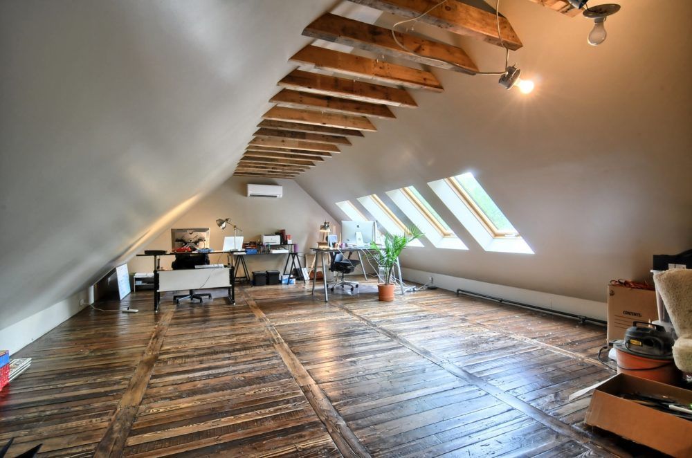 A large attic with a wooden floor and lots of windows.