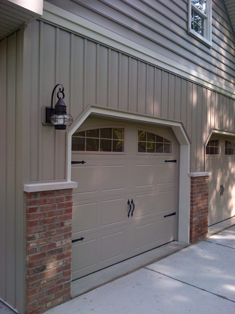 A garage door with a brick pillar on the side of it