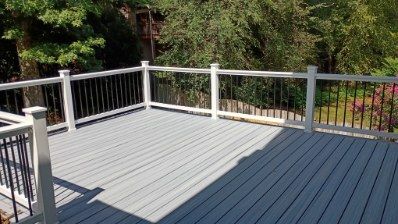 Gray deck with white railing and black spindles, overlooking trees.