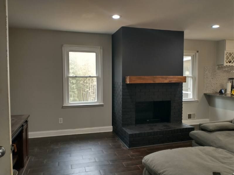 Living room with dark gray brick fireplace and wood mantel, gray walls, and dark flooring.