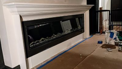 Modern, angled fireplace built into a white wall with black trim, under a white mantel.