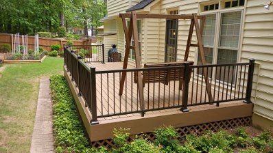 Wooden deck with railing, swing, and garden in backyard setting.