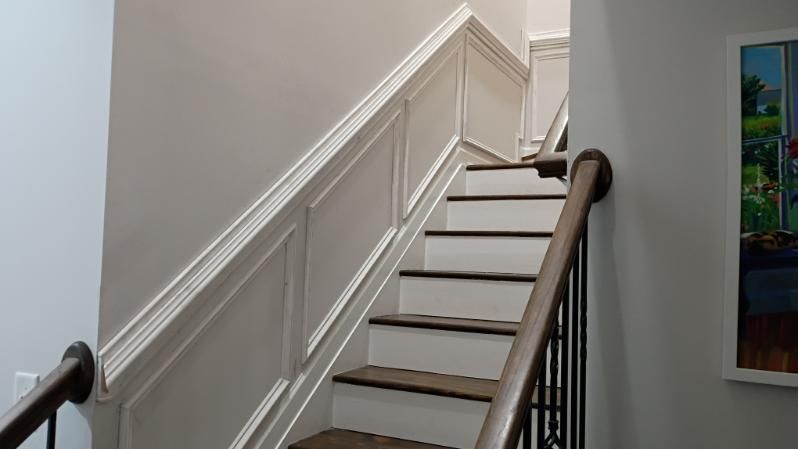Staircase with white walls, brown handrails, and wooden steps leading upwards.