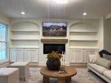 Living room with built-in shelves, fireplace, TV, and light-colored furniture.