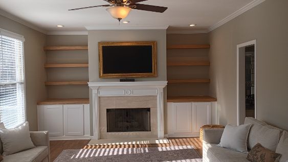 Living room with a fireplace, built-in shelves, TV, and cream-colored furniture.