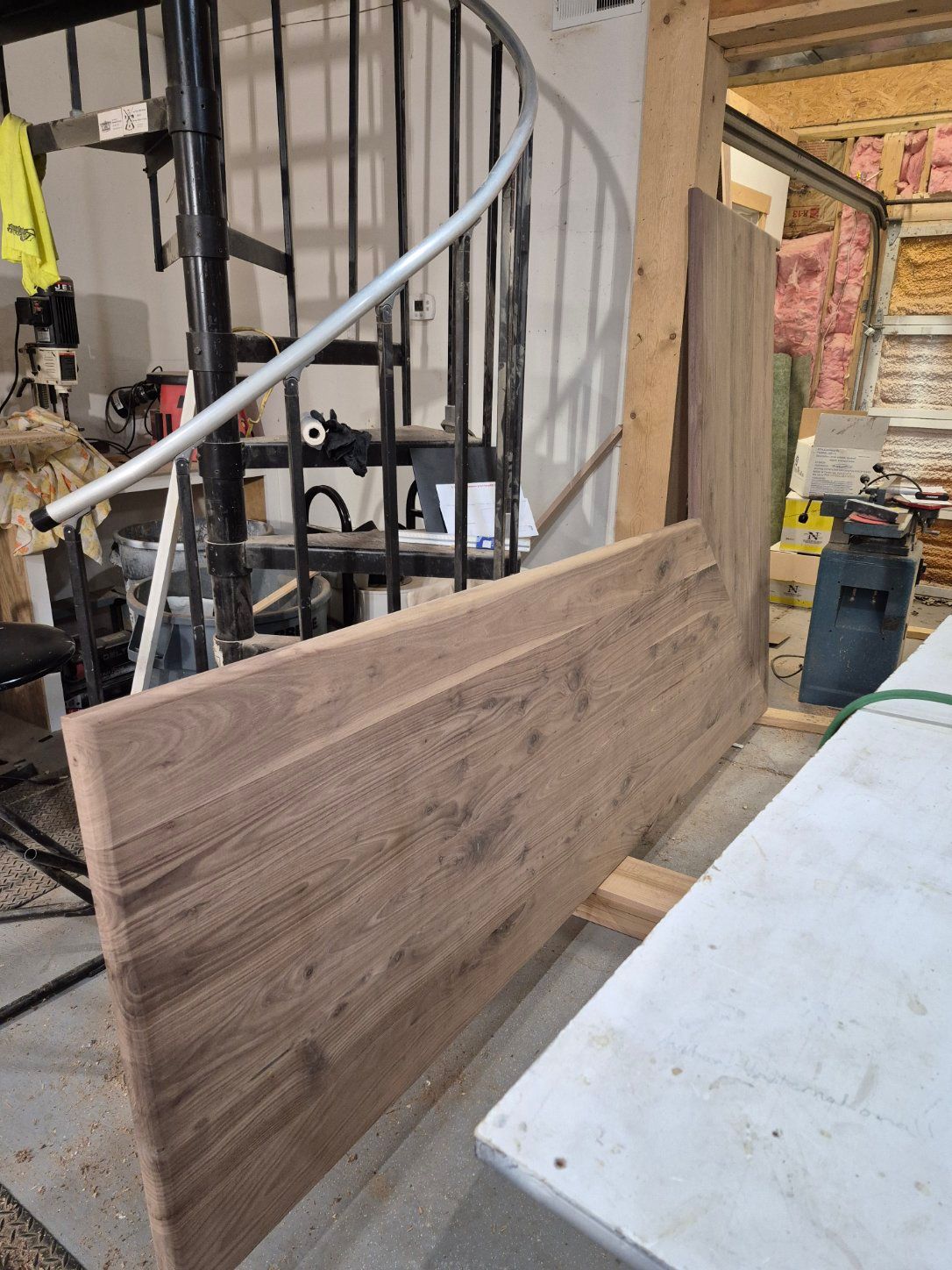 Wooden boards near a spiral staircase in a workshop.