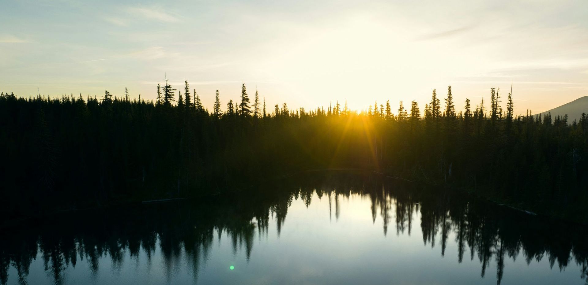 The sun is setting over a lake surrounded by trees.