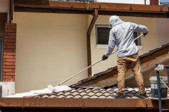 Professional painters working on a roof painting in Townsville QLD currently adding undercoat paint into the rooftop using a roller at a residential property.