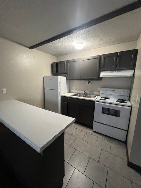 Small kitchen with black cabinets, white appliances, and a white countertop island.