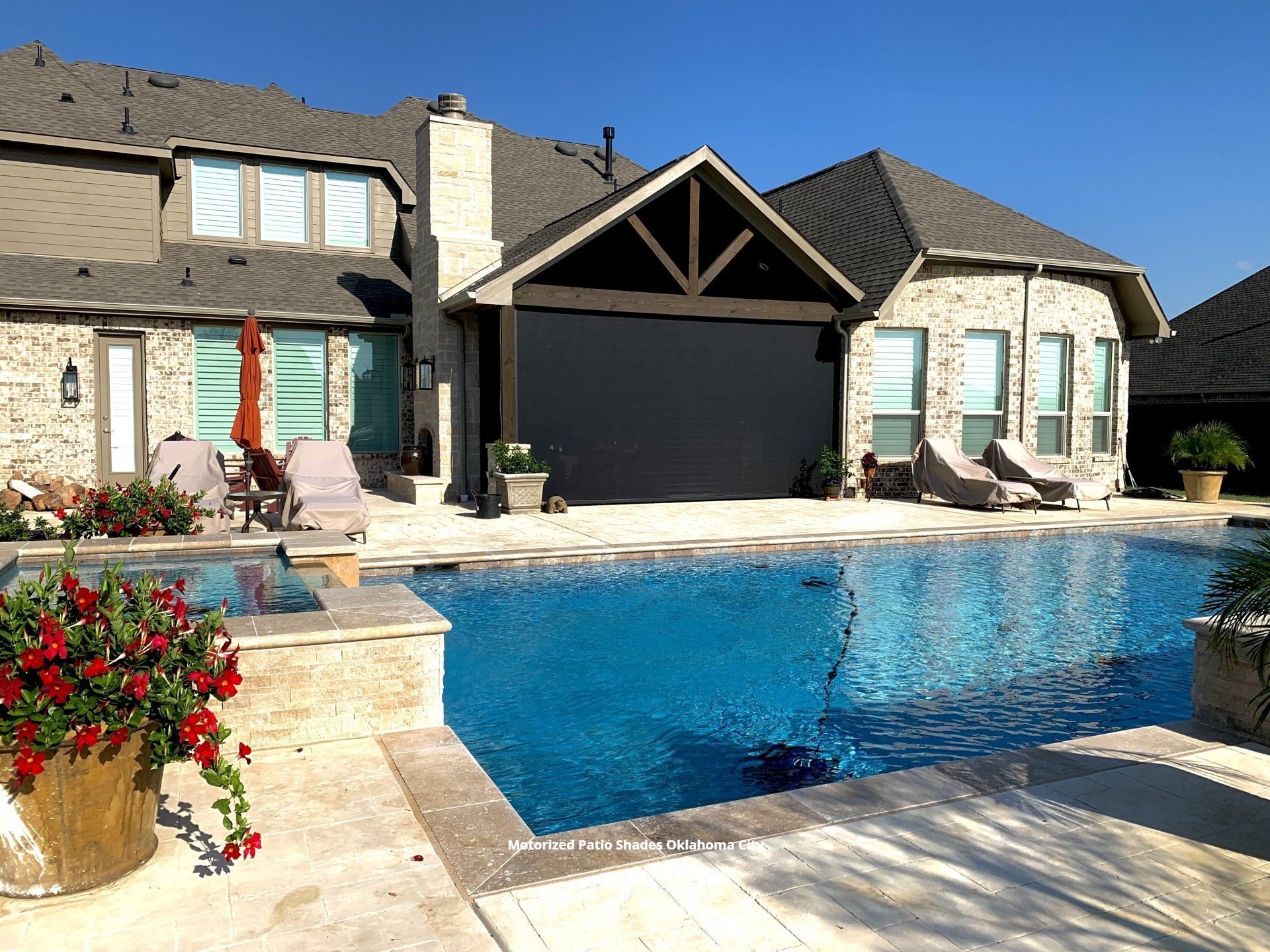 a large swimming pool in front of a brick house with motorized exterior patio shades in oklahoma city
