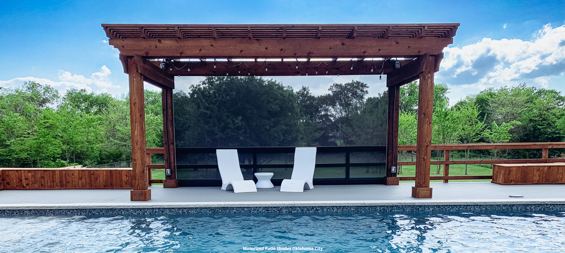 two chairs sit under a pergola overlooking a swimming pool with a retractable sun screen