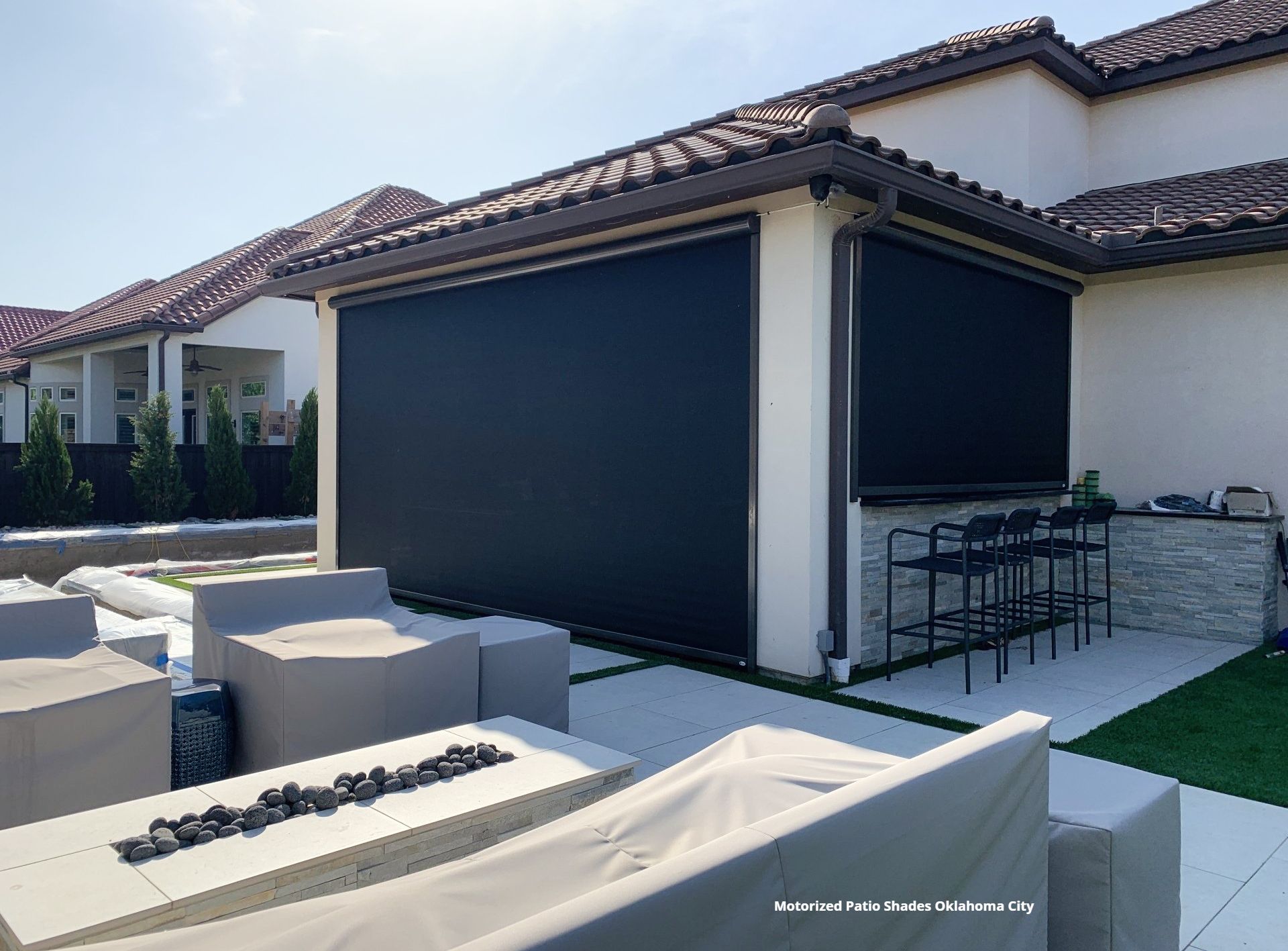 a patio area with a fire pit and a couch with loered motorized patio screens