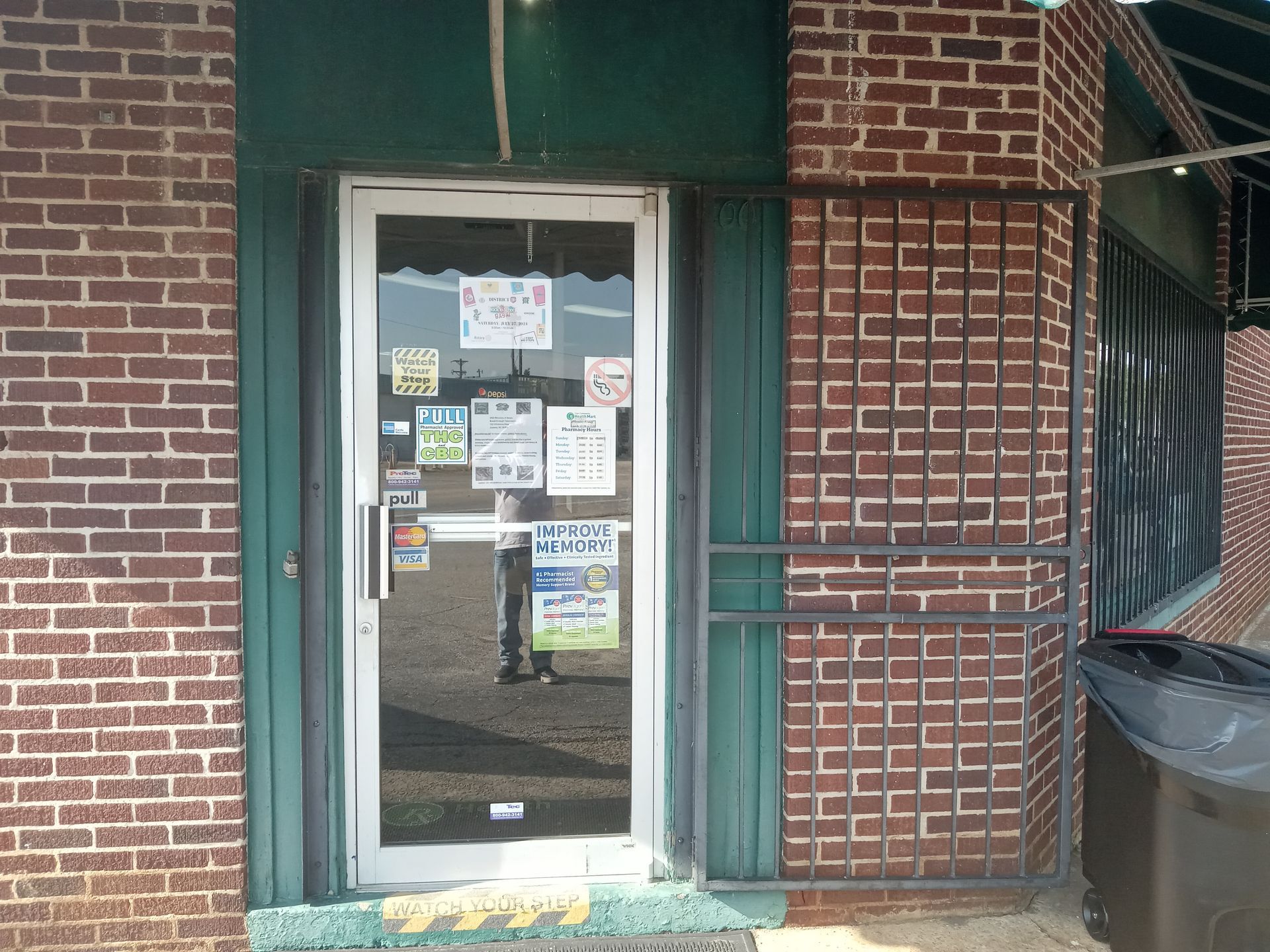 A brick building with a glass door and a green awning.