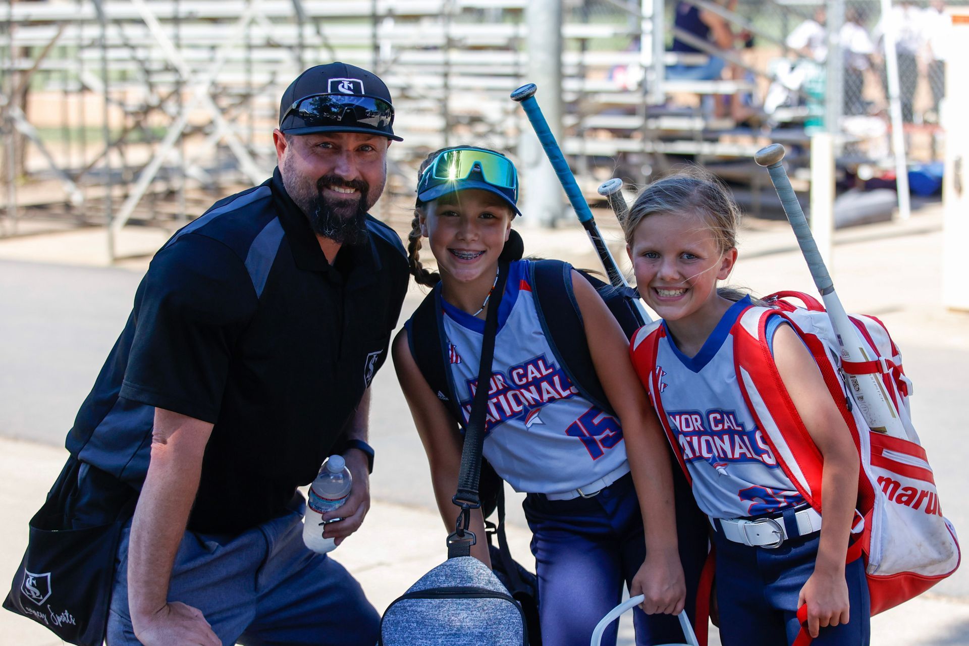 A coach is giving each of the girls a high five on a baseball field.