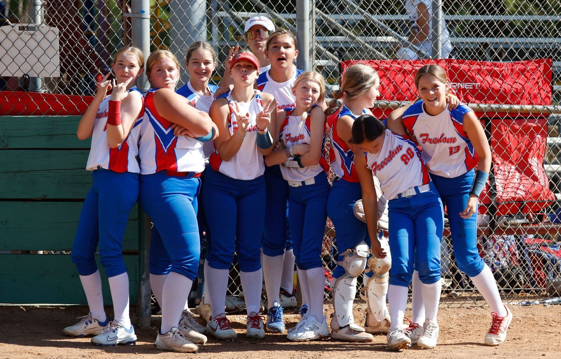 A group of young girls in softball uniforms are posing for a picture
