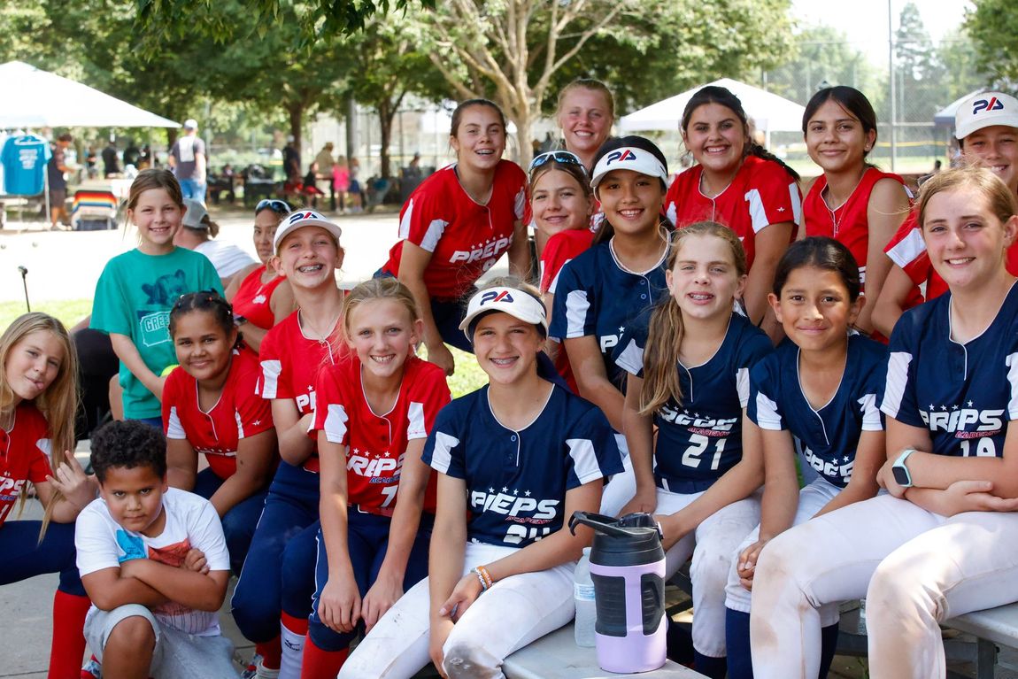 A group of young girls in softball uniforms are posing for a picture