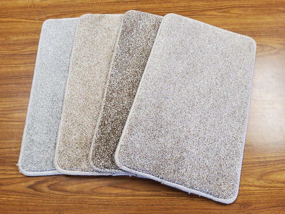 Four textured rectangular floor mats in light gray and beige on a wood surface
