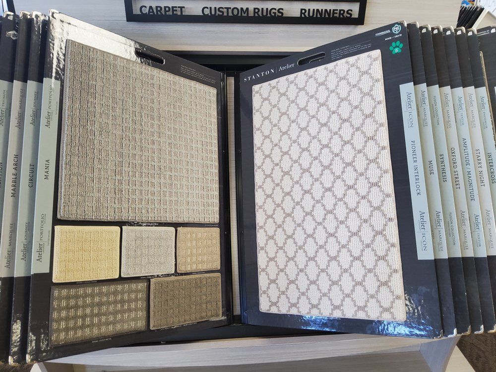 Open carpet sample book with beige and patterned swatches in a showroom