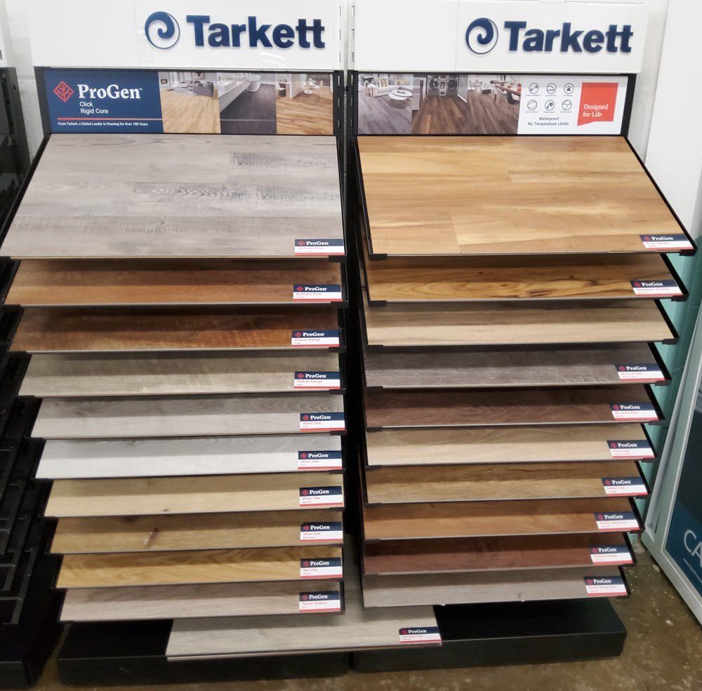 Tarkett flooring display with sample planks in assorted wood tones and gray finishes on a retail rack