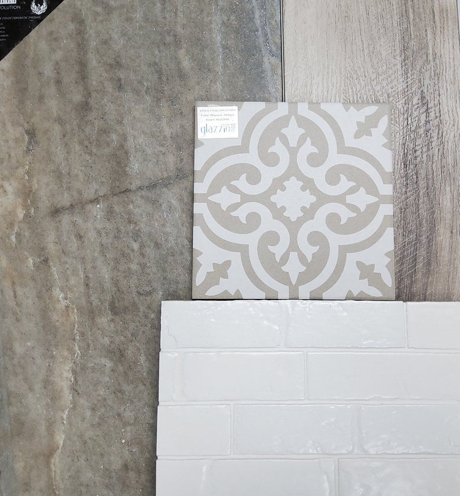 Two tile samples: gray patterned tile above white brick-style tile against a wood-look background