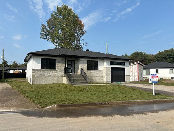 Une maison avec un panneau à vendre devant.