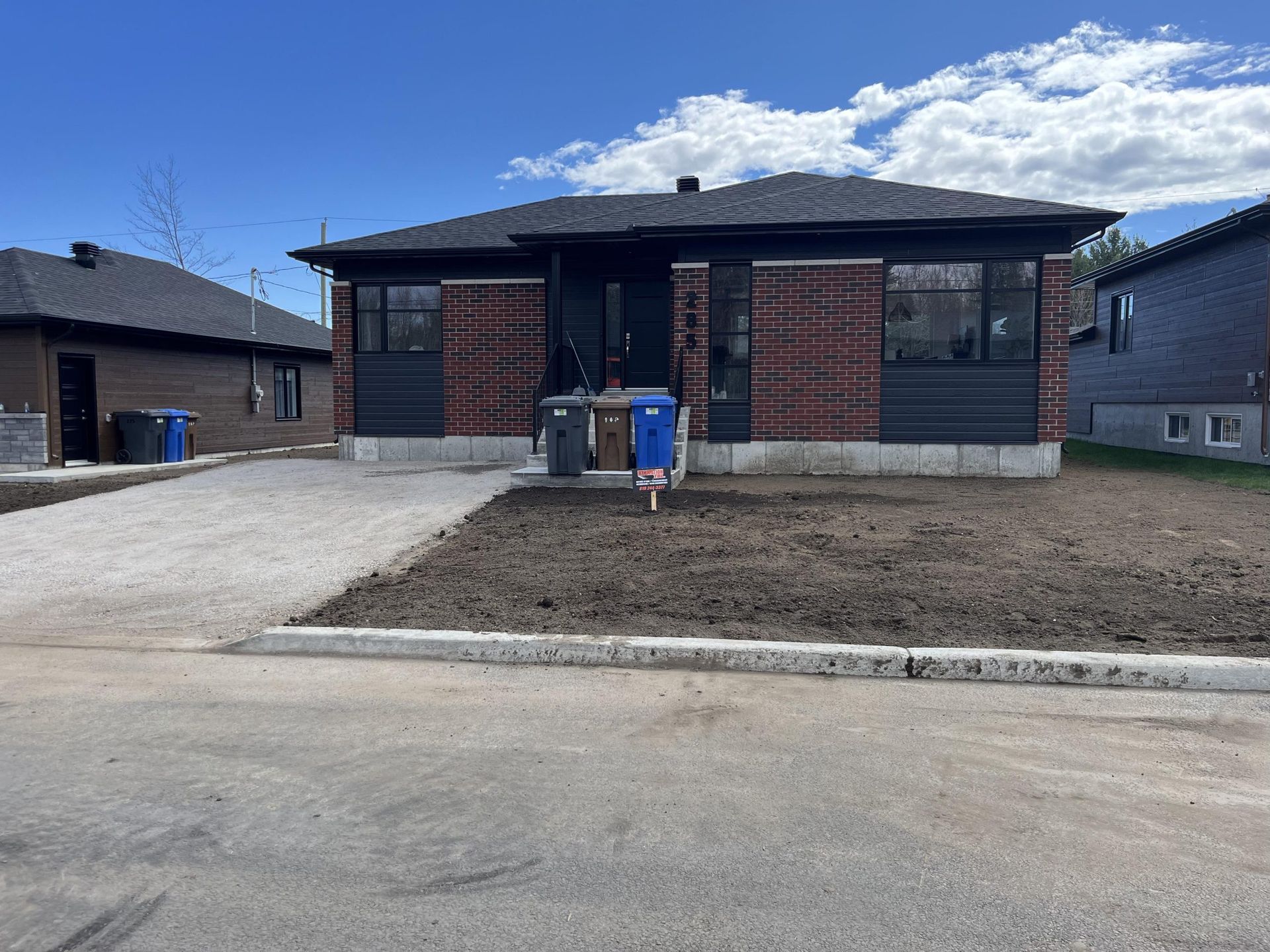 Une maison en briques avec une poubelle bleue devant