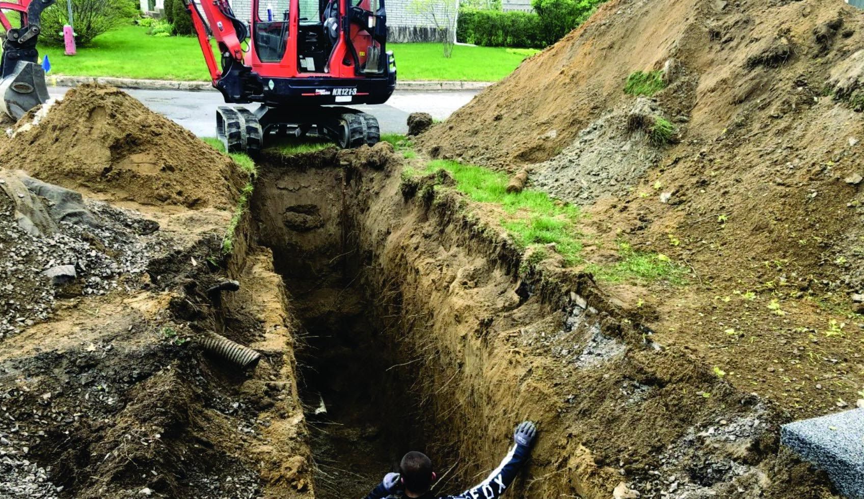 Une petite excavatrice creuse un trou dans le sol.