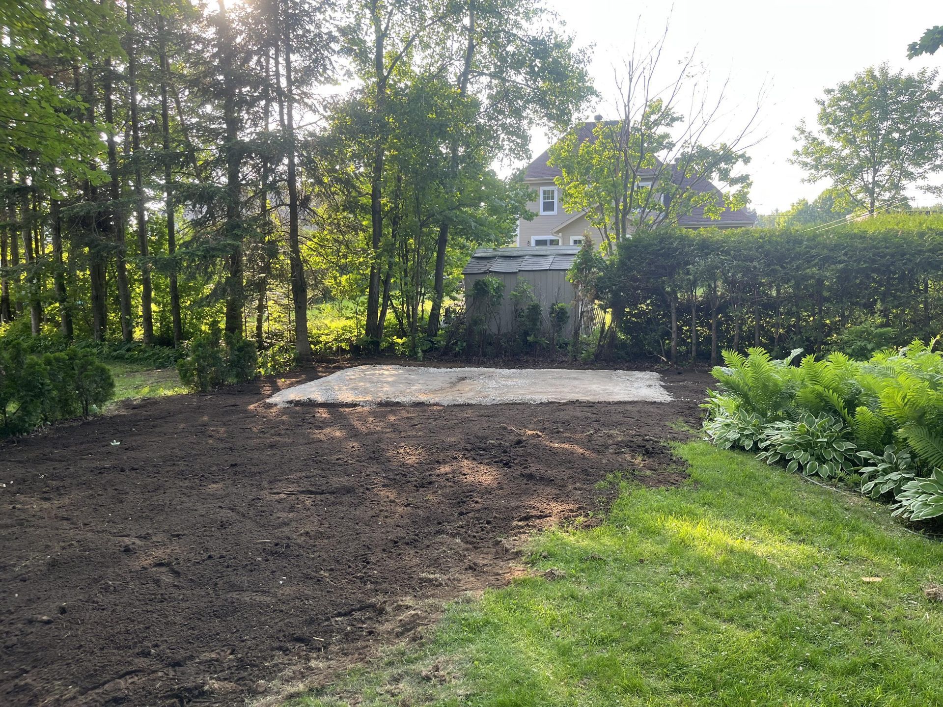 Un champ de terre avec un hangar en arrière-plan et des arbres en arrière-plan.