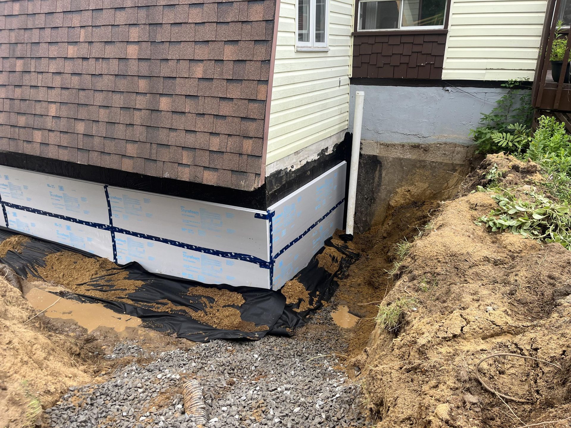 Une maison avec un système de drainage en cours d'installation sur le côté.