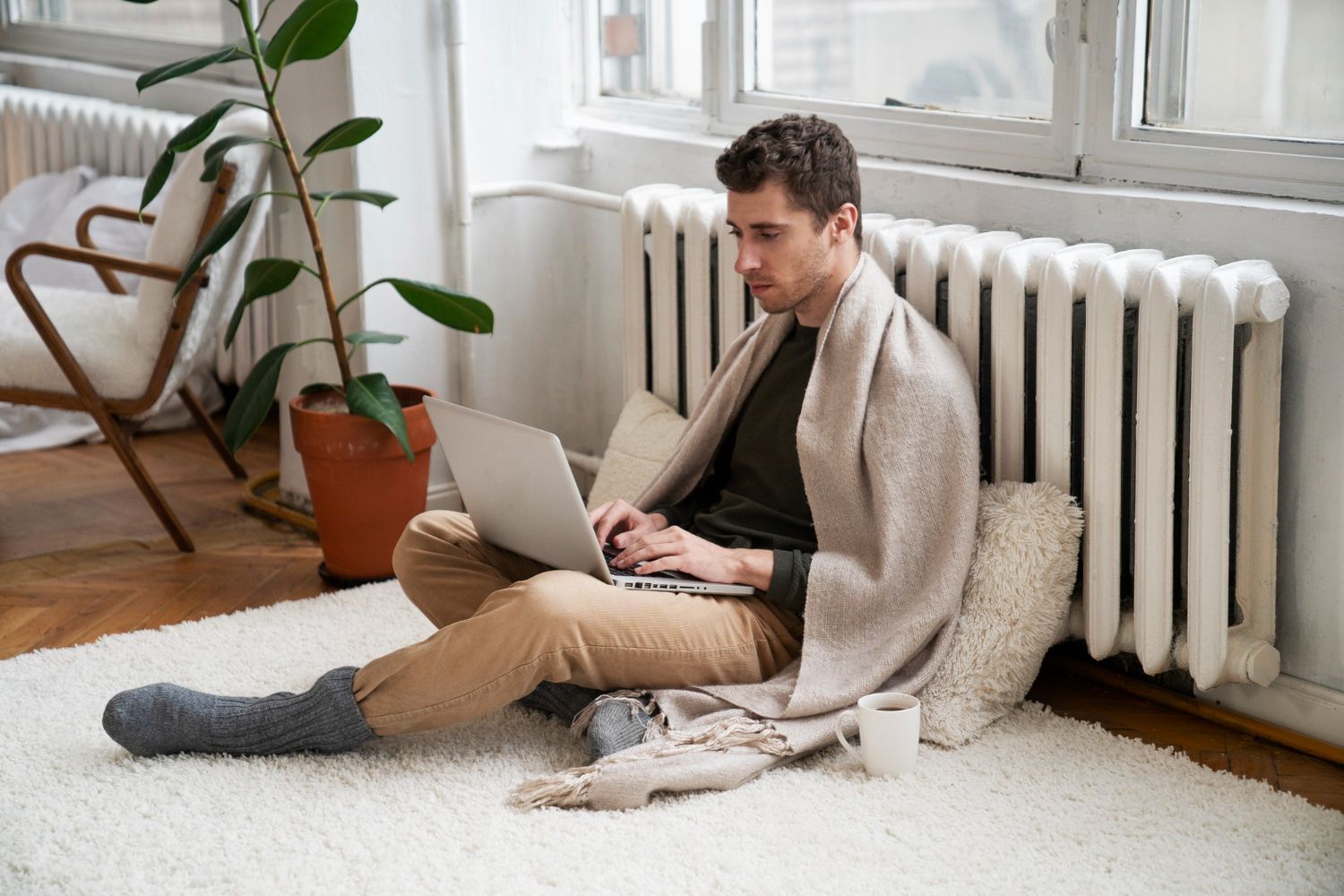 A man is sitting on the floor using a laptop computer.