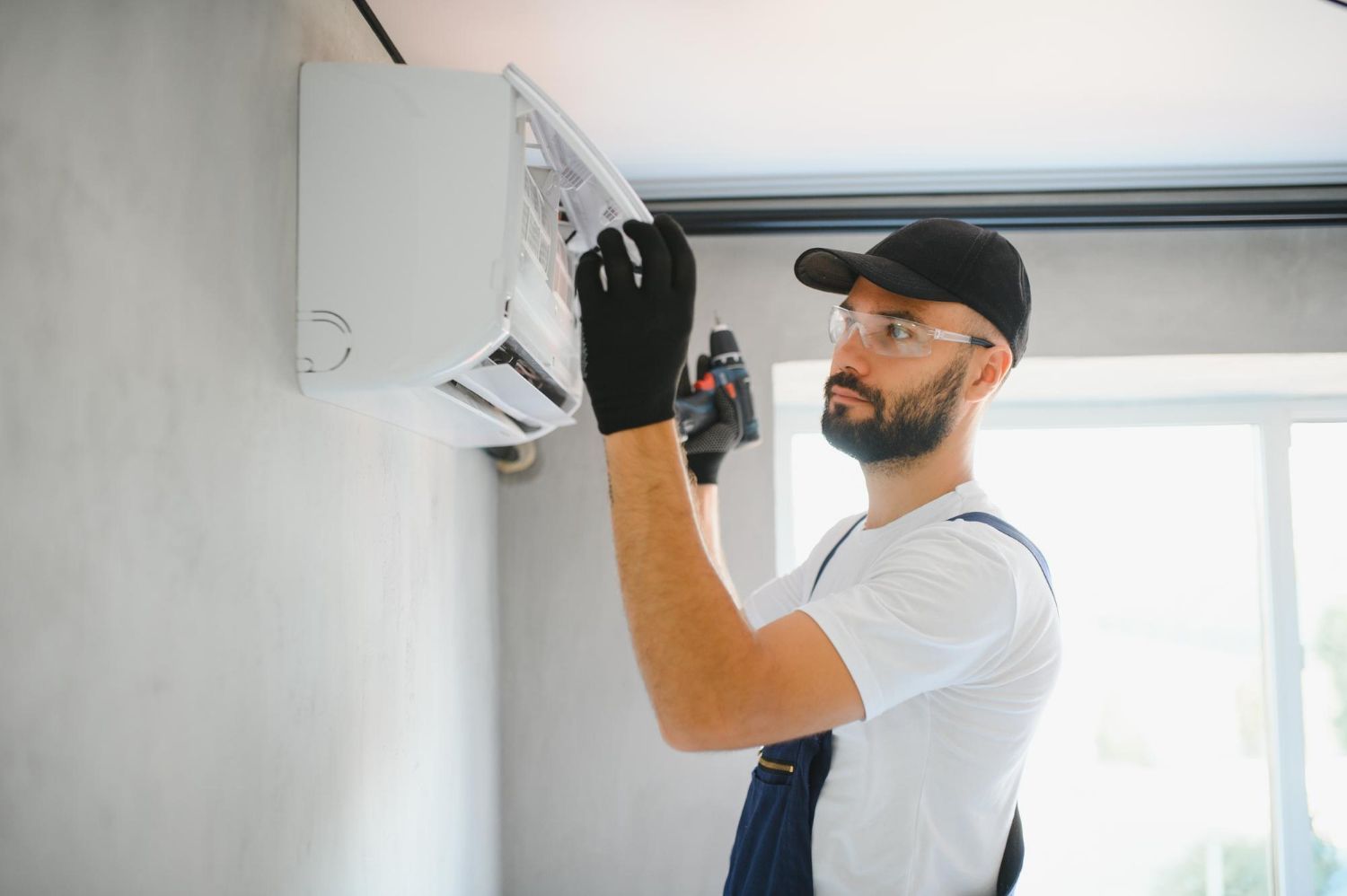 A man is installing an air conditioner on a wall.