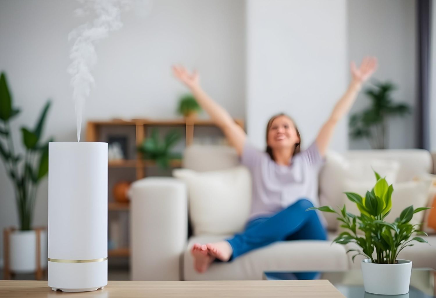 A woman is sitting on a couch in a living room with her arms in the air.