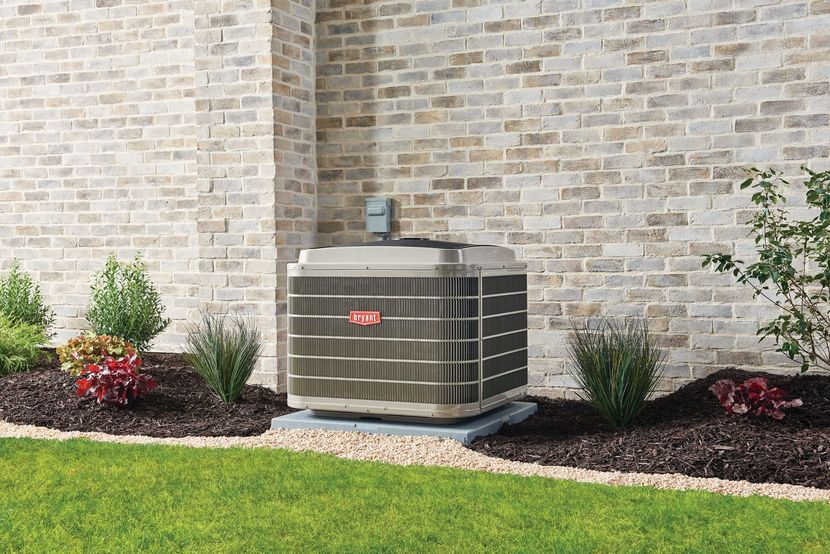 An air conditioner is sitting on the side of a brick building.
