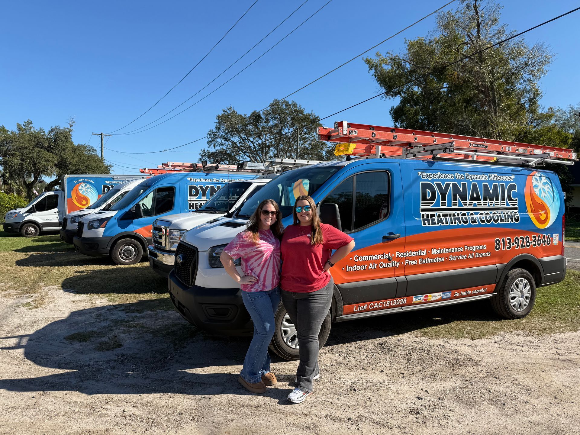 Two women are standing in front of a row of vans.