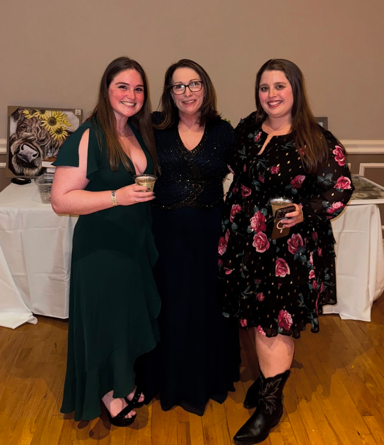 Three women in dresses are posing for a picture in a room.