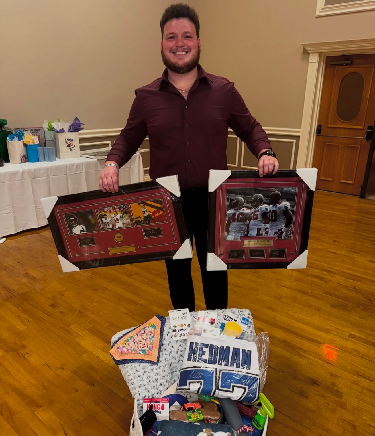 A man holding two framed pictures in front of a box that says redman
