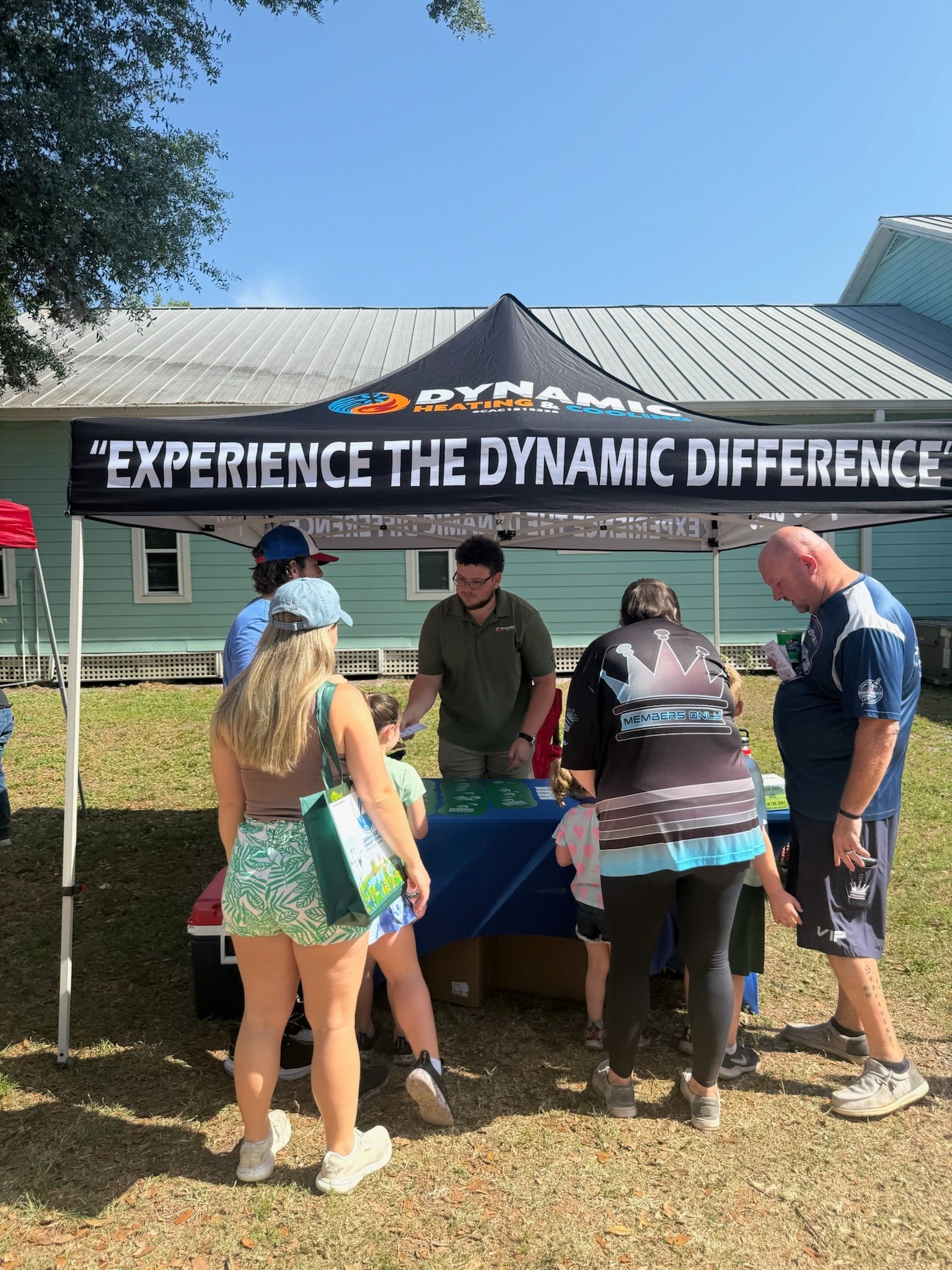A group of people are standing around a table under a tent that says `` experience the dynamic difference ''.