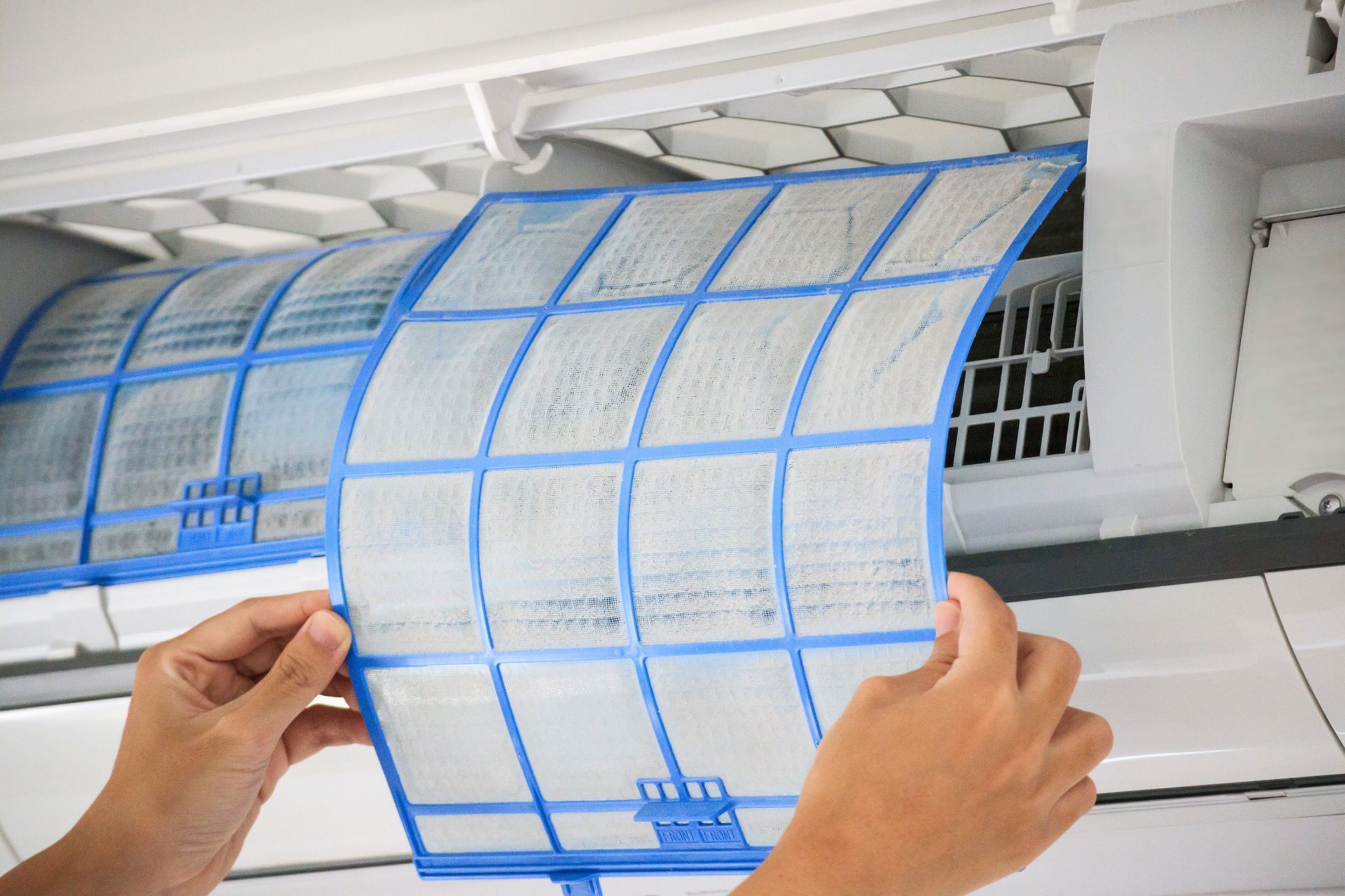 a person is cleaning a filter on an air conditioner .