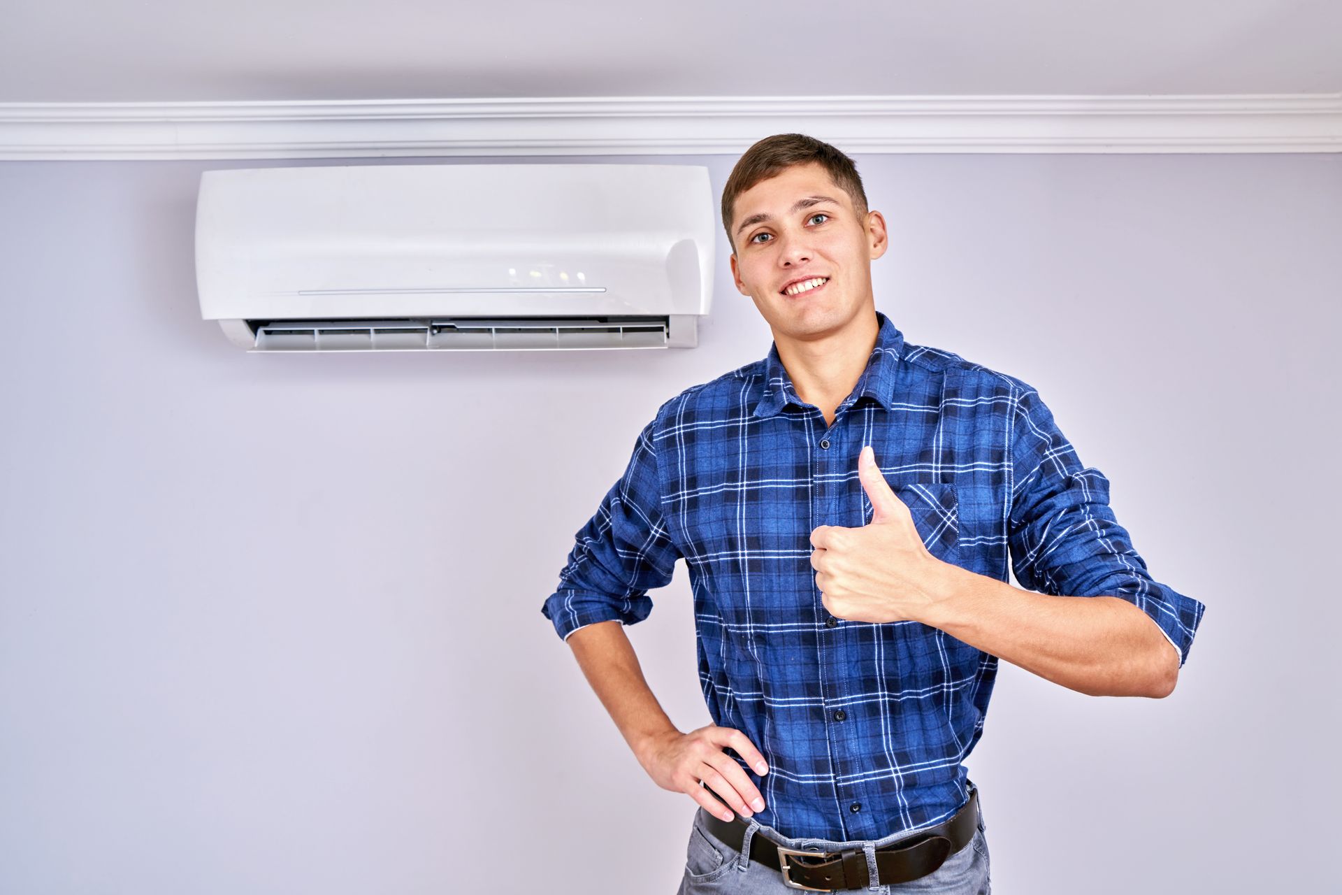 A man is giving a thumbs up in front of an air conditioner.