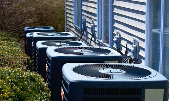 a row of air conditioners are lined up outside of a building .