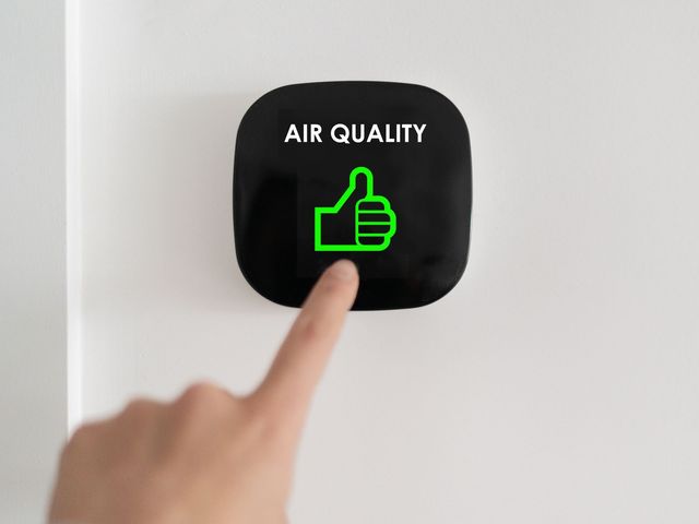 a person is pressing a button on a wall that says `` air quality '' .