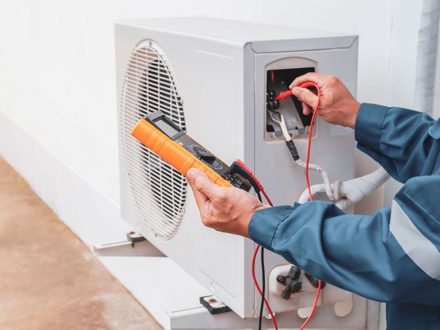 a man is fixing an air conditioner with a multimeter .