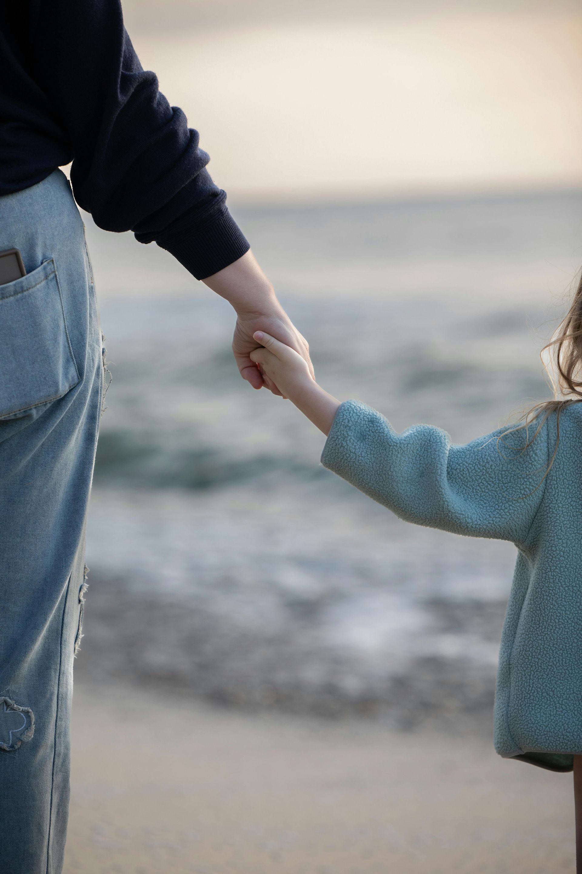 Two people holding hands on a beach by the ocean
