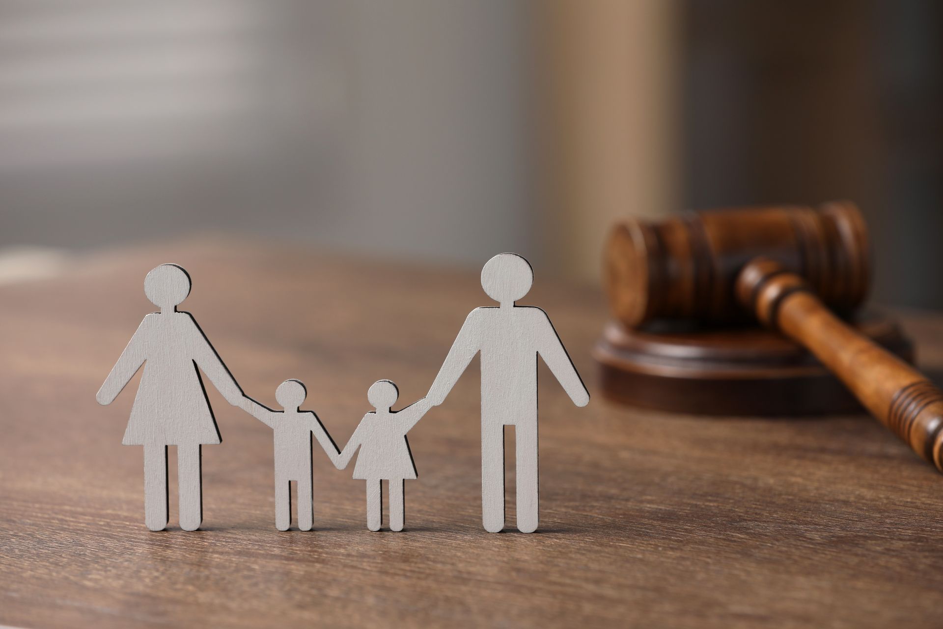 Paper family figurines beside a judge’s gavel on a wooden table