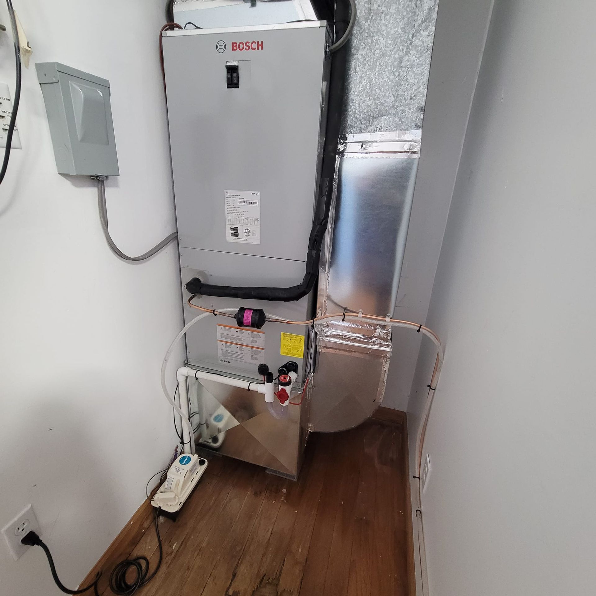 HVAC system unit installed in a closet with ductwork and external electrical components.