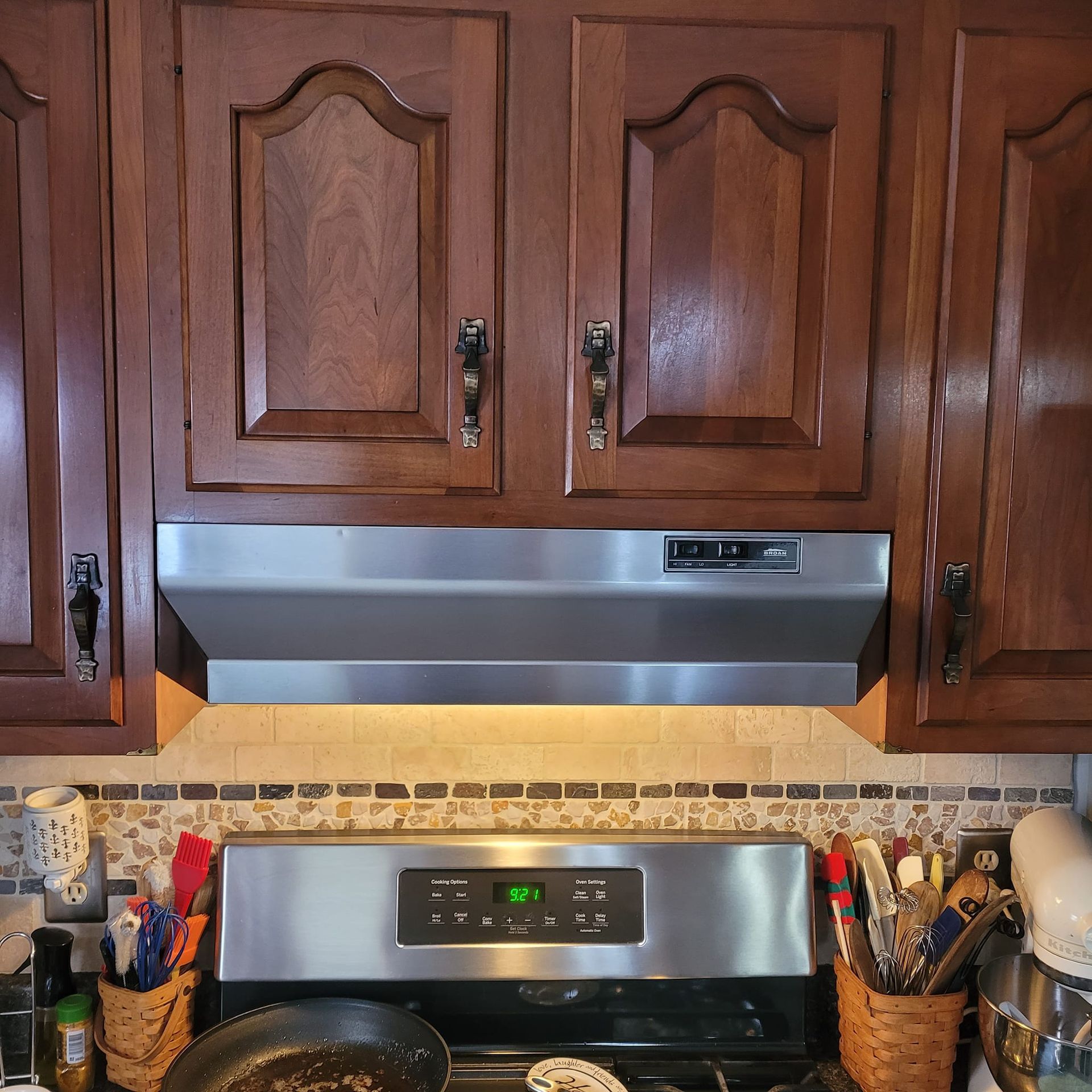 Kitchen cabinets above a stainless steel range hood and stove.