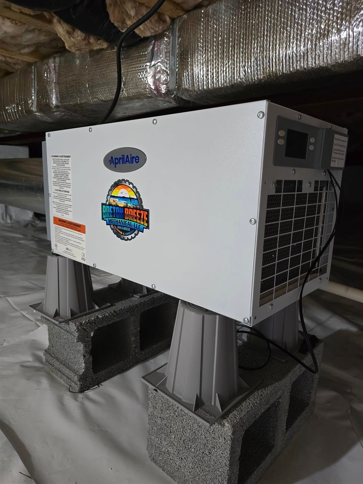 White water heater elevated on cinder blocks in a crawl space.