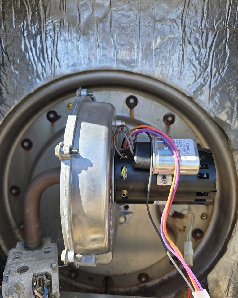 Close-up of a furnace component with a blower motor, wiring, and metal housing.