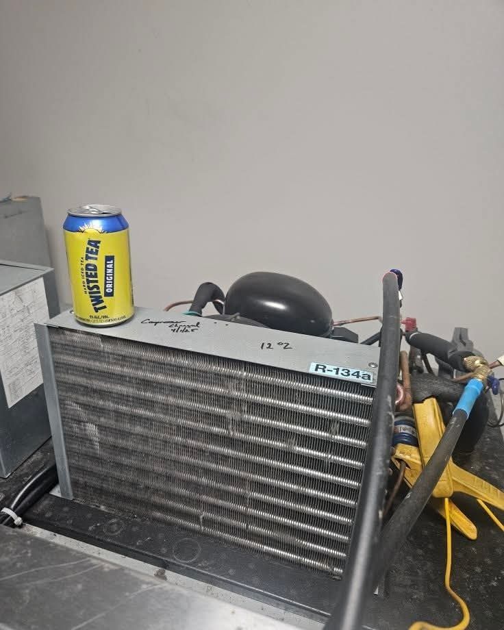 Refrigeration unit with a Twisted Tea can on top. Equipment has tubes, wires, and a black component.